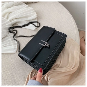 Detailed macro view of black leather crossbody bag with white stitching and H-shaped buckle