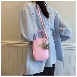 Detailed side view of a stylish pink crossbody phone bag with silver heart charm and strap
