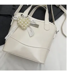 Detail of cream white bucket bag with pearl heart pendant and lace bow decoration