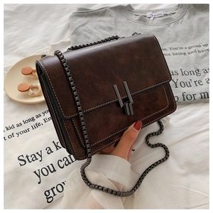 Detail of vintage dark brown faux leather bag with gunmetal buckle and chain strap