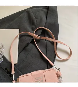 Detail of light pink woven texture crossbody bag with silver logo and adjustable strap