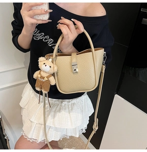 Detail of beige lychee pattern bucket bag with silver turn-lock and cute bear charm