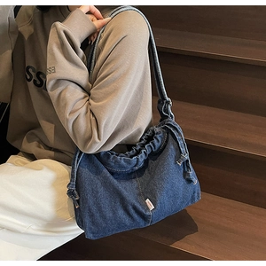 Détail du sac cabas en jean bleu avec fermeture à cordon plissé et bandoulière