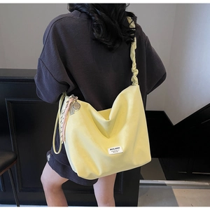 Detail view of the yellow canvas tote with ruffled strap and mini tennis racket charm