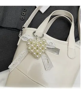 Detail of cream bucket bag featuring a pearl heart charm and lace bow on a dark blazer