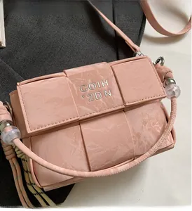 Close-up of pink woven handbag with silver logo and decorative crystal bead handles