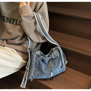 Vue détaillée d'un sac cabas en denim bleu avec plis à cordon et petite étiquette rose