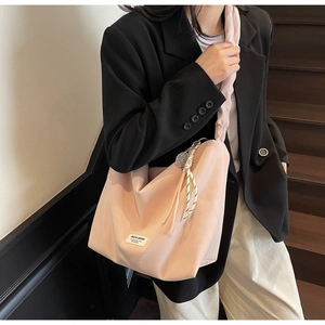 Pink tote bag detail with cloud-like ruffled strap and black-white woven charm accessory