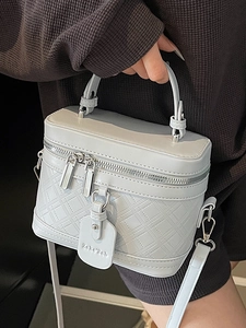 Light blue quilted leather box bag with silver hardware and top handle shown handheld