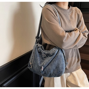 Gros plan d'un sac à bandoulière vintage en denim bleu avec plis et cordon de serrage