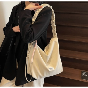 Close-up of a cream-white tote bag with a unique ruched shoulder strap design