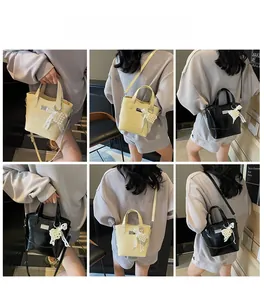 Detail view of stylish bucket bag showing pearl bow charm and polished leather texture