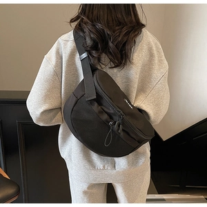 Détail du sac bandoulière sport noir avec panneau en maille et sangle réglable sur mannequin