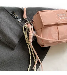 Close-up of pink woven texture handbag with delicate strap on grey fabric background