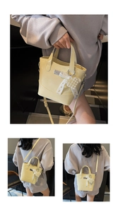 Detailed macro view of pale yellow bucket bag with lace bow and pearl charm ornament