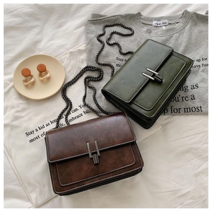 Macro view of olive green and brown leather crossbody bags with metal buckle