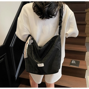 Detail of black tote bag featuring ruched cloud strap and tennis racket charm