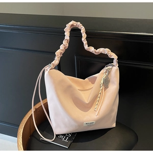 Detail of light pink hobo bag with ruffled cloud handle and decorative logo tag