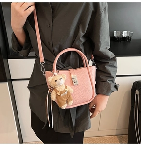 Pink lychee texture leather bucket bag with cute plush bear charm and metal buckle detail
