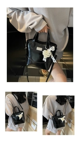 Detail of glossy black bucket bag with pearl bow charm and adjustable shoulder strap
