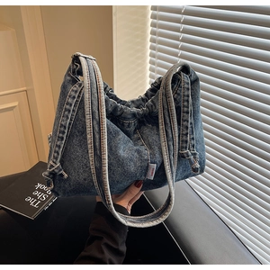 Détail du sac cabas en denim bleu délavé avec texture froncée et étiquette tissée