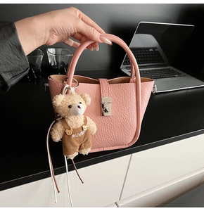 Pink lychee grain leather bucket bag featuring a cute plush bear charm with metal clasp