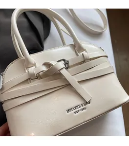 Detailed shot of cream shell handbag showing cross strap design and soft leather texture