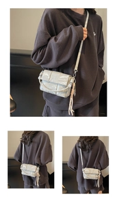 Detail of silver-grey woven crossbody bag with metallic crinkled texture and flap
