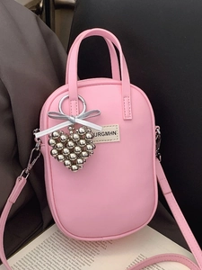 Pink synthetic leather crossbody phone bag with heart charm on minimalist open book