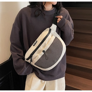 Gros plan sur le sac de poitrine crème avec poche en filet noir et détail du logo