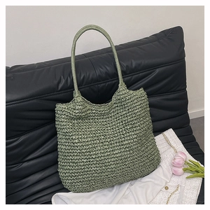 Detailed close-up of light green straw woven tote bag with circular handles on a sofa