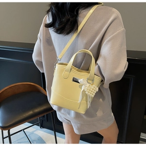 Detail view of yellow patent leather bucket bag with pearl heart charm and lace bow