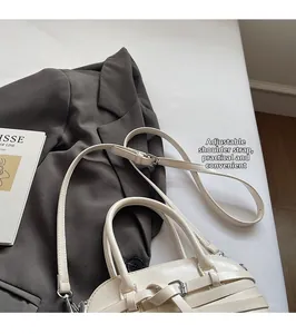 Detail of cream leather shell bag with woven design and adjustable strap on a blazer