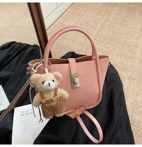 Detail view of pink bucket bag with lychee texture and cute bear doll charm accessory