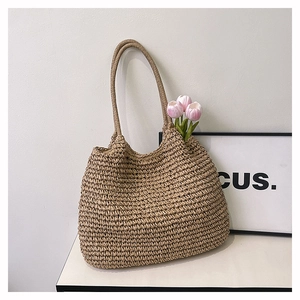 Close-up detail of natural woven straw tote bag with textured knit pattern and long handles