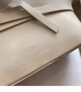 Detailed view of the creamy white leather texture and embossed MIKAXIQI logo on a shell bag