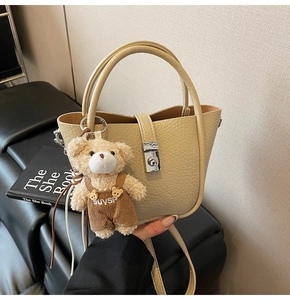Detail of light beige lychee pattern bucket bag with cute plush bear charm and silver clasp