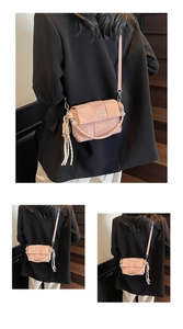 Detail of pink woven small square bag featuring a rope tassel charm and sleek strap