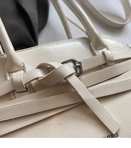 Close-up of cream PU leather shell bag featuring cross strap buckle and silver hardware