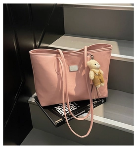 Detailed texture of pink lychee leather tote bag with a cute bear plush keychain