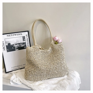 Detail of hand-woven straw tote bag with intricate texture and minimalist shoulder strap