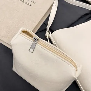 Close-up of cream textured faux leather pouch with silver metal zipper and hardware details