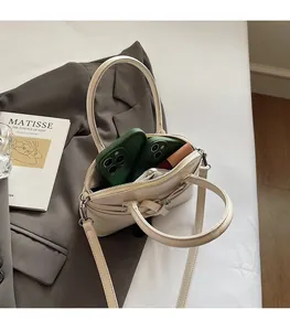 Detail view of spacious off-white handbag interior holding two phones and a lipstick