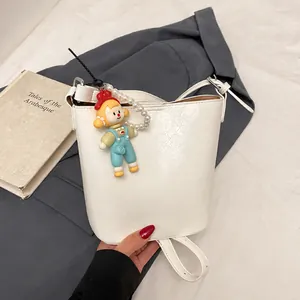 Detailed top view of a white minimalist bucket bag with a cartoon pearl charm and leather texture