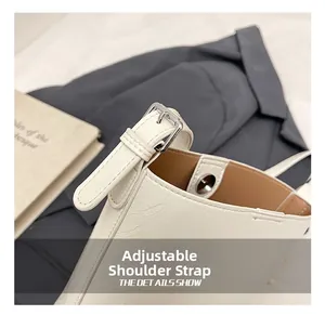 Detail of adjustable shoulder strap on white bucket bag with silver buckle hardware