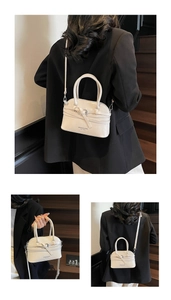 Macro view of white shell bag with polished finish and detachable metal strap buckles