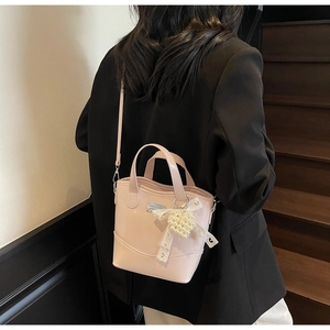 Pink mini bucket bag with pearl heart charm and lace bow shown on shoulder in detail