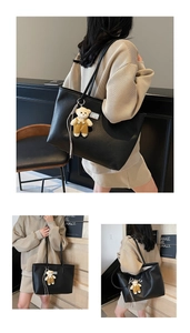 Detail of black pebbled leather tote bag with a cute teddy bear charm and twin shoulder straps