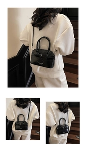 Detail of black patent leather shell bag showing glossy texture and shoulder strap