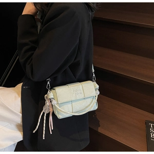 Detail of light green woven mini crossbody bag featuring a unique tennis racket charm